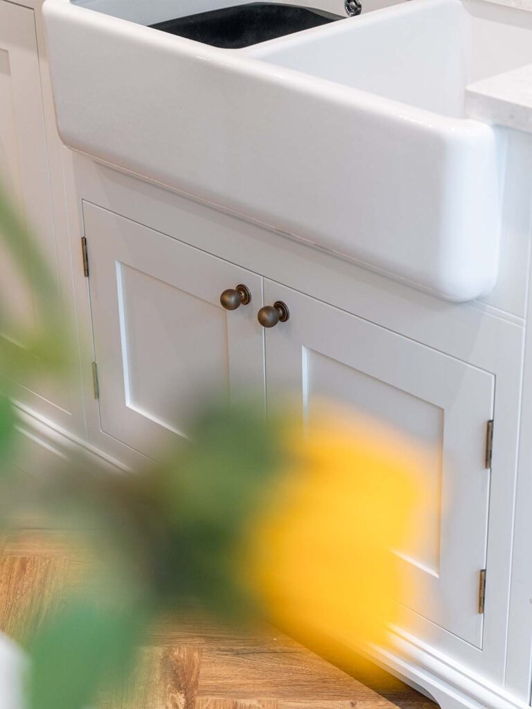 A close-up of a bright blue kitchen island with an integrated sink and a sleek faucet. The island has a white countertop with a subtle pattern and a wooden breakfast bar attached, showcasing the blend of classic and modern design.